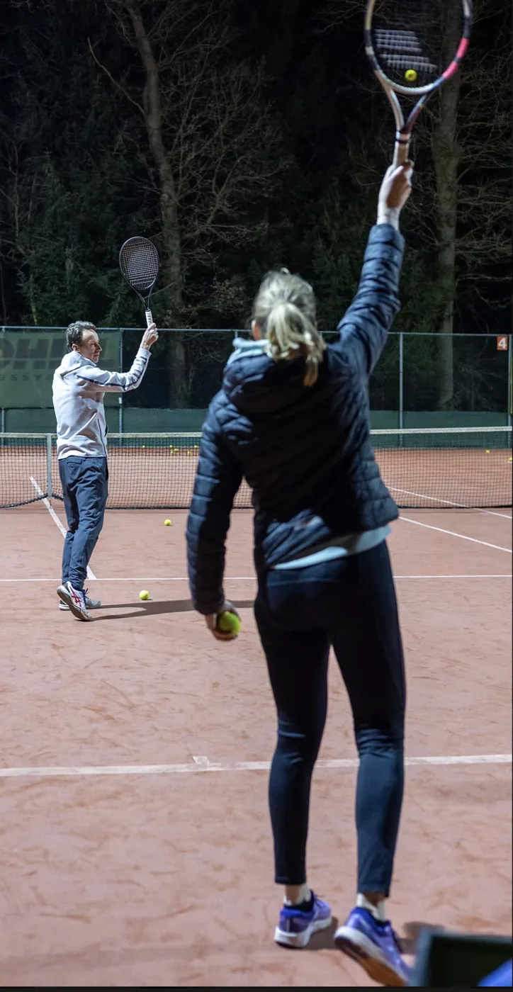 Tennisles waarbij de trainer een speler aanwijzingen geeft